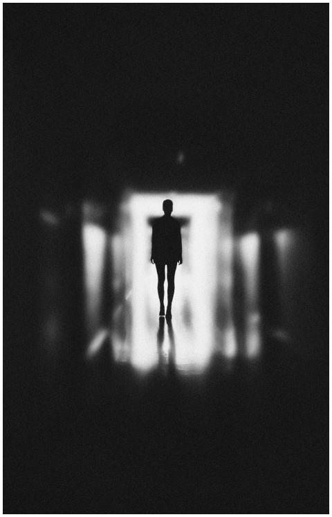 Moody silhouette of a person in a blurred, black a