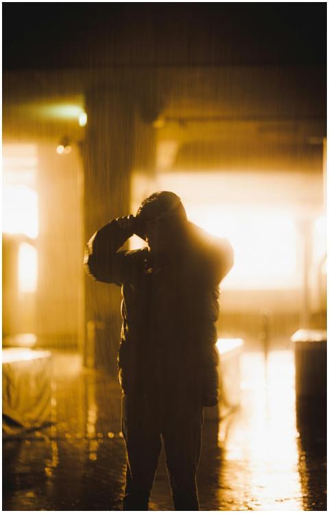 A silhouette of a person wearing a jacket standing