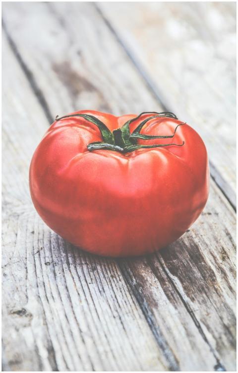 Close-up of a ripe red tomato on a rustic wooden s