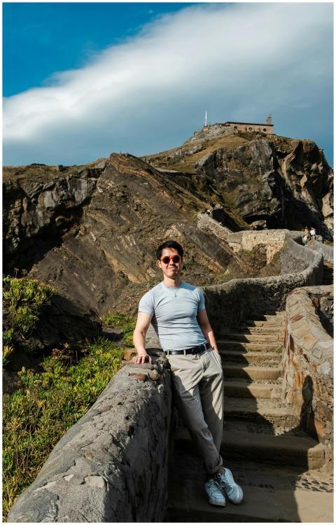 Man posing on stone steps at scenic coastal viewpo