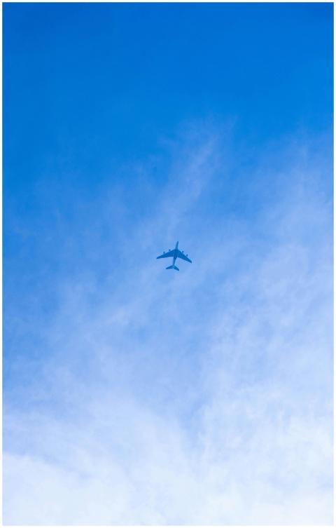 A lone airplane soaring through a bright blue sky