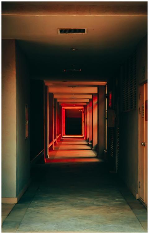 Eerie empty hallway with red and black shadows cre