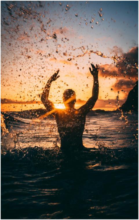 Silhouette of a person enjoying the ocean at sunse