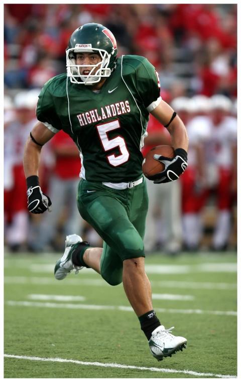 High school football player in green uniform runni