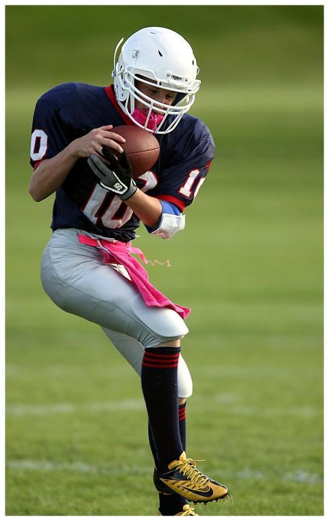 Youth football player catching a pass during a gam