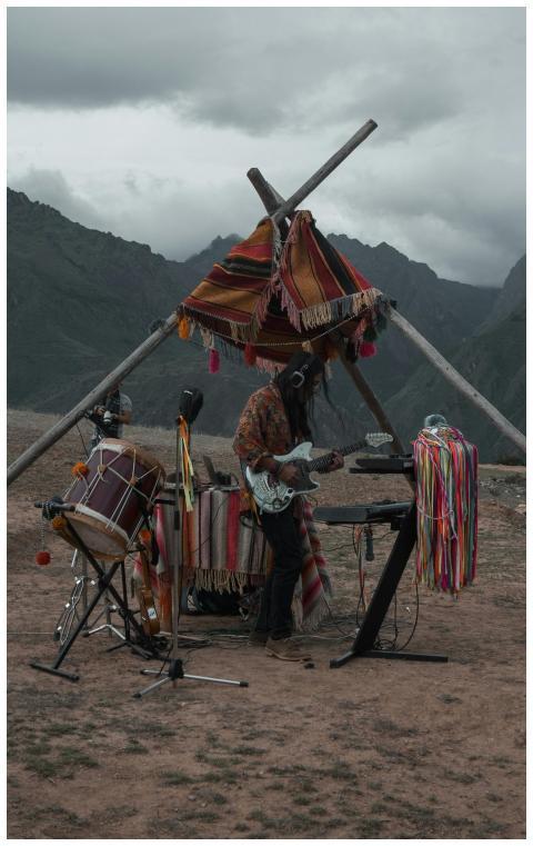 Guitarist playing outdoors under a colorful tent i
