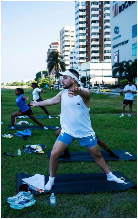 Group practicing yoga outdoors in city park with m