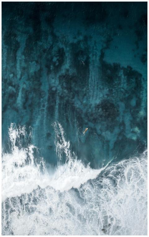 A breathtaking aerial view of a lone surfer naviga