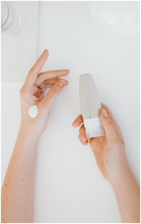 A person's hands applying skincare cream from a tu