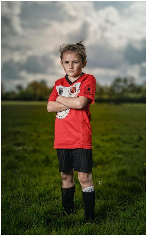 Confident young boy in a red football jersey stand