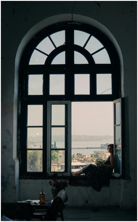 A woman sits by a window overlooking Bakü, capturi