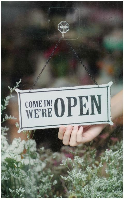A welcoming open sign in a flower shop window with