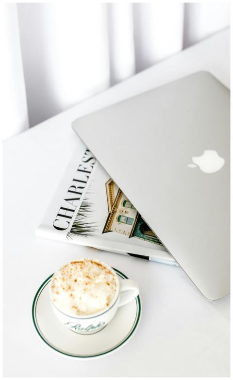 A sleek laptop beside a cappuccino on a bright, mo
