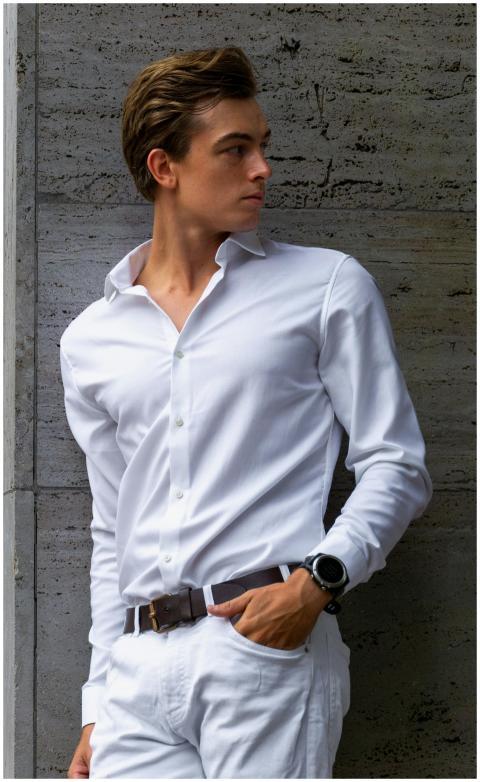 Confident young man in white outfit posing against
