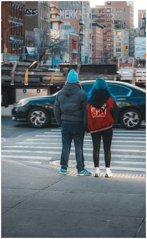 Two people in winter clothing waiting at a crosswa