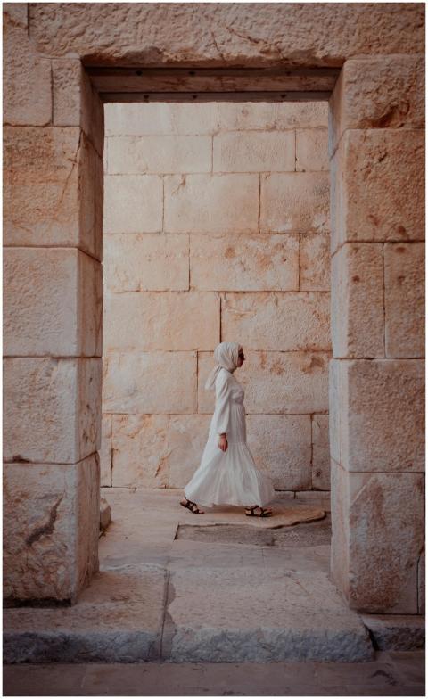 A woman in a white dress and headscarf walks throu