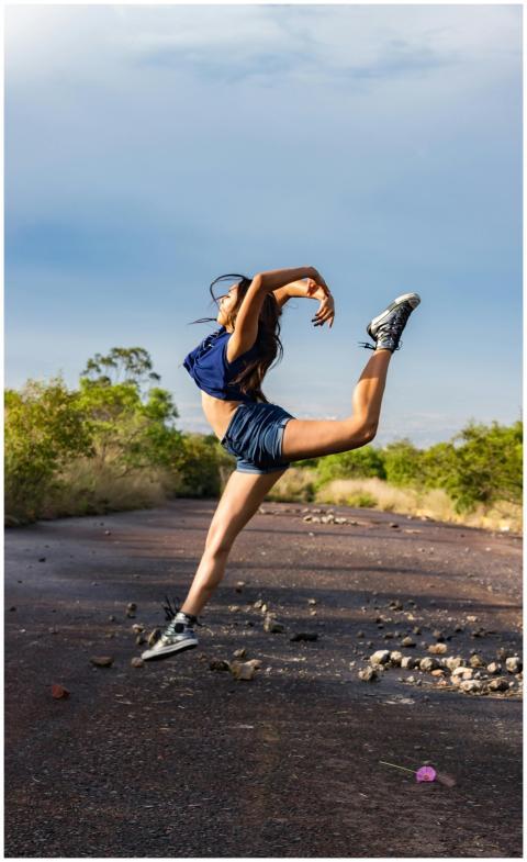 A woman performs a graceful dance leap on a sunlit