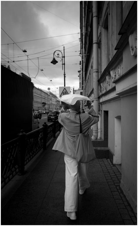 A woman walks under an umbrella on a rainy city si