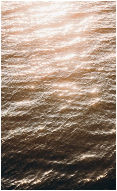 Glistening sunlight on ocean waves at sunset creat
