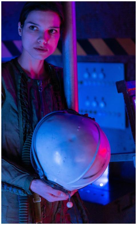 Portrait of a spacewoman holding a helmet in a fut