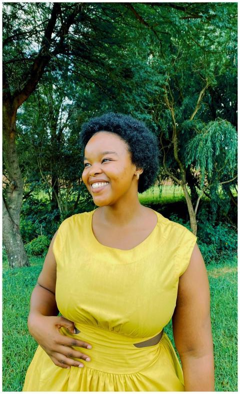 A joyful woman in a yellow dress stands in a vibra