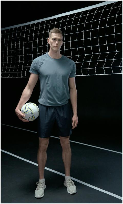 Young male volleyball player in sportswear holding
