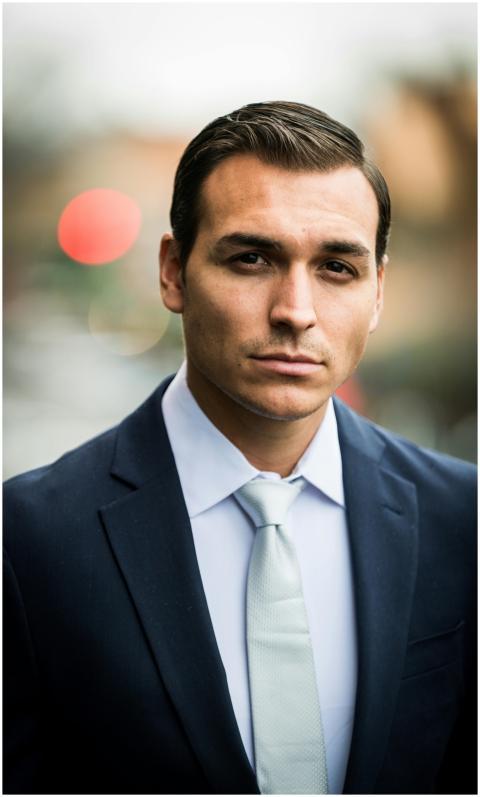 A confident businessman in a suit poses with a def