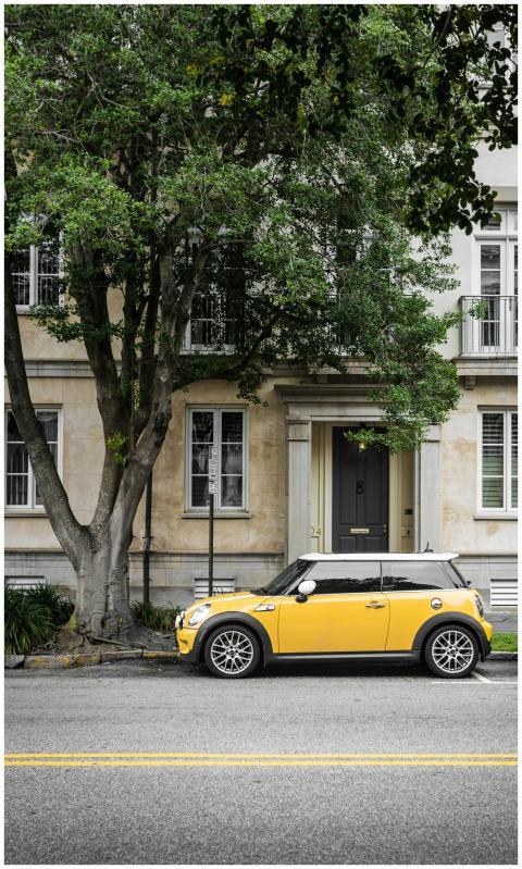 A vibrant yellow Mini Cooper parked on a scenic st