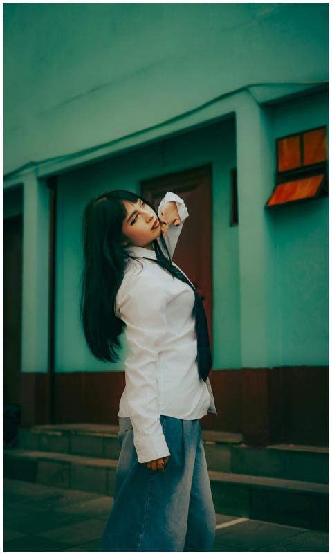 Woman in white shirt and tie posing stylishly agai