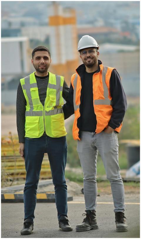 Two construction workers wearing safety vests and