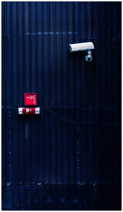 Modern security camera and exit sign on a corrugat