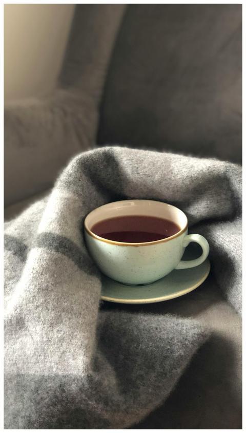 A warm cup of coffee nestled in a soft gray blanke