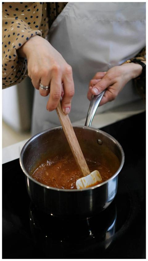 Close-up of a cook stirring a savory sauce in a sa