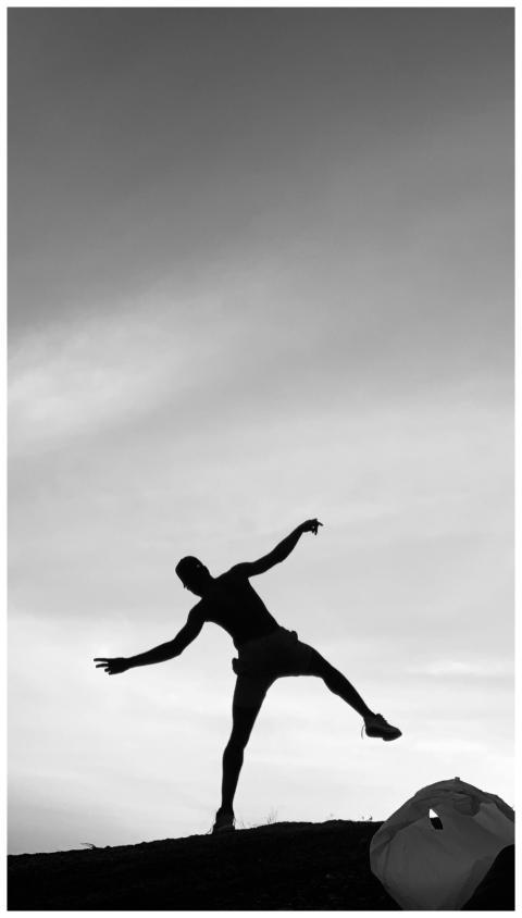 Dramatic silhouette of a person balancing on a hil
