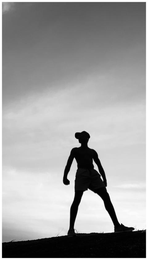 Silhouette of a person standing strong against a d