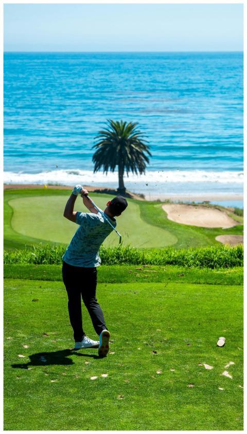 Golfer swinging on a picturesque golf course by th