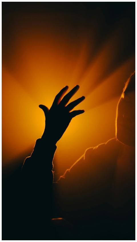 Silhouette of an outstretched hand with warm backl