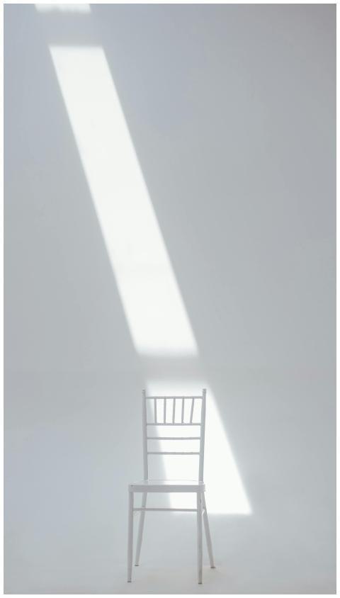 A white chair in a minimalistic setting with sunli