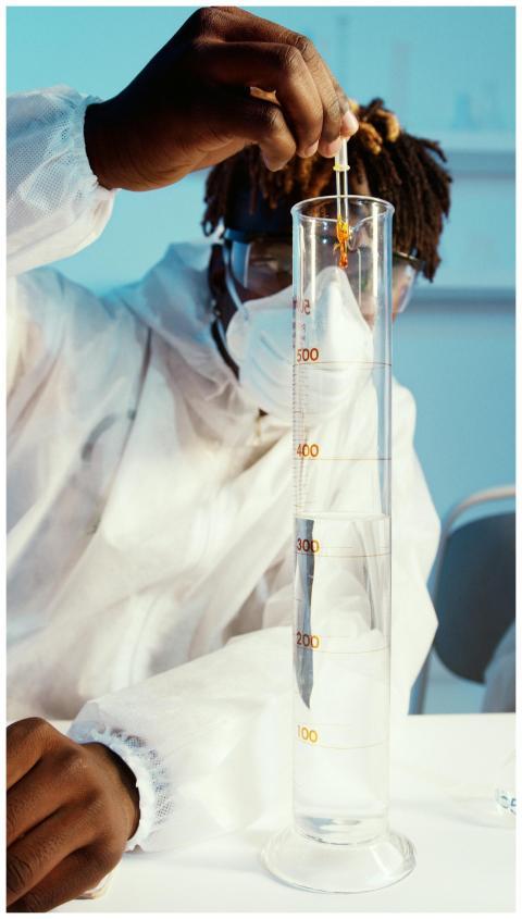 Scientist in protective gear using a dropper in a