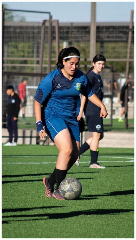 Two teenage girls in sports uniforms playing socce