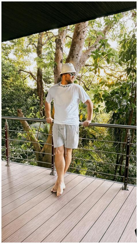 Man standing on a wooden balcony surrounded by lus