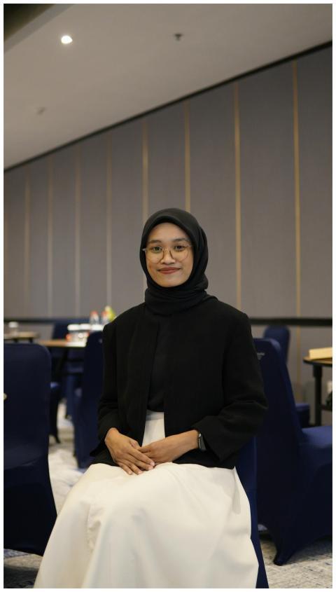 A smiling businesswoman wearing a hijab, seated in