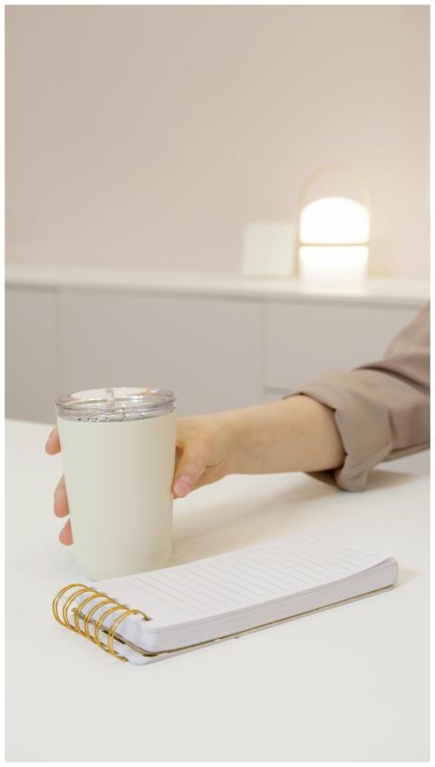 A minimalist workspace with a hand holding a cup,