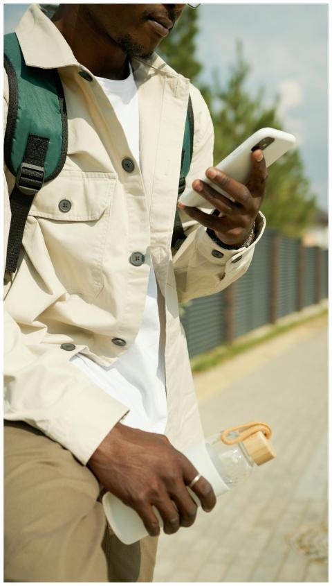 Young man with backpack using cellphone while walk
