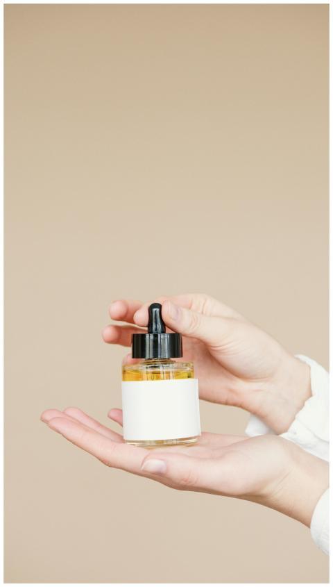 Close-up of hands holding a glass dropper bottle f