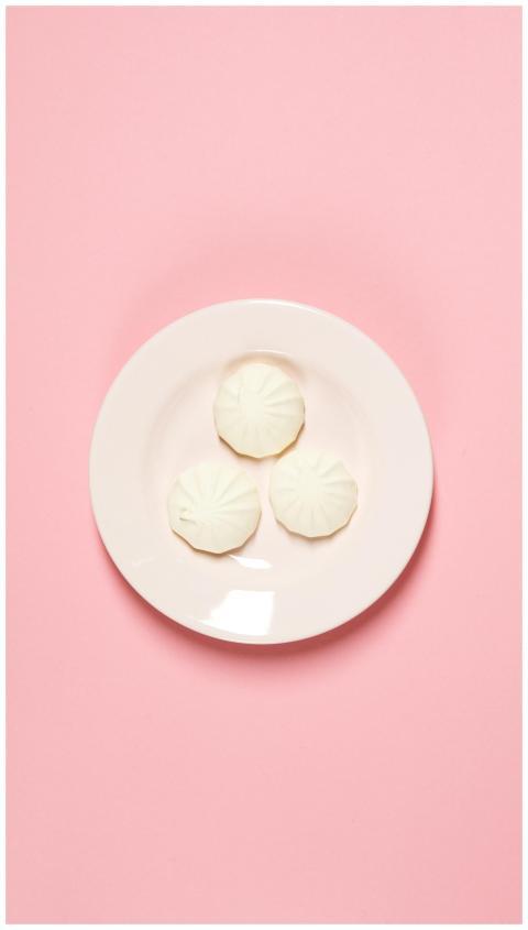 Three white meringue cookies on a plate against a
