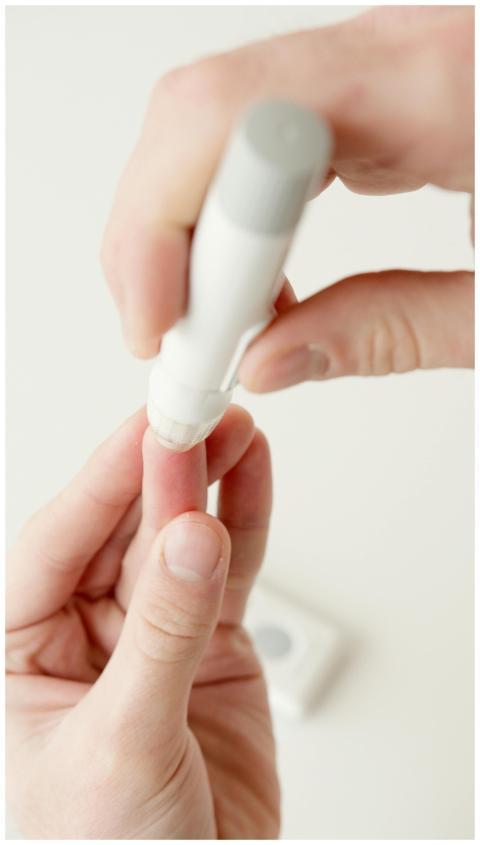A person using a lancet pen to check blood sugar l