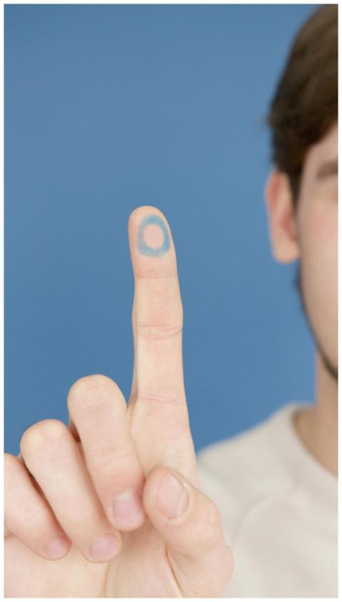 Close-up of a hand with a blue circle symbolizing