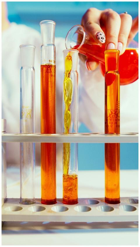 Close-up of a lab technician pouring orange liquid