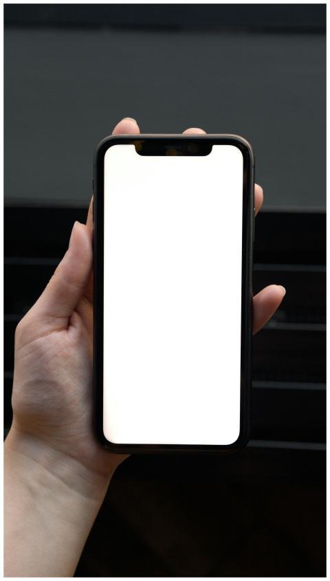 Close-up of a hand holding a smartphone with a bla